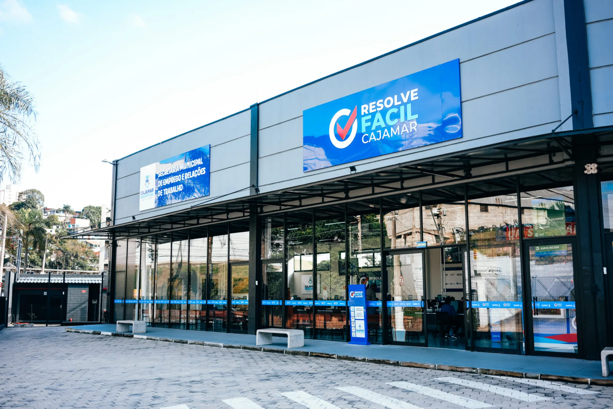 Fachada de vidro do Resolve Fácil Cajamar, com placas azuis do serviço e da Secretaria Municipal de Emprego e Relações de Trabalho.