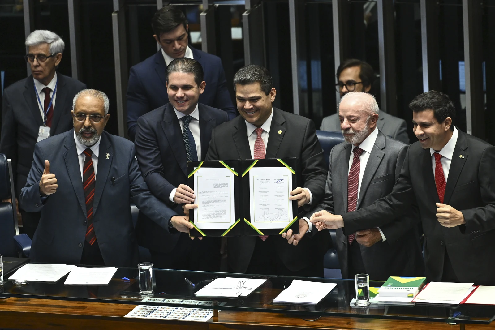 Davi Alcolumbre mostra o documento promulgado ao lado de Lula, Hugo Motta e integrantes da mesa do Congresso.