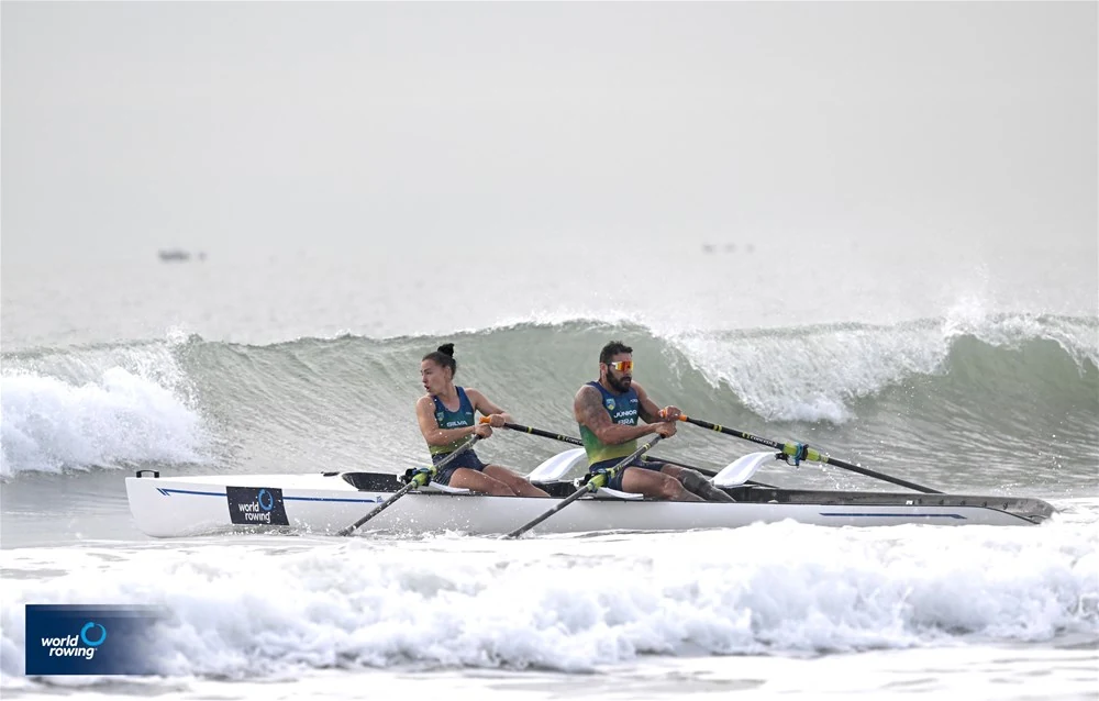 Joice Emily e Valdeni Júnior remam juntos em uma embarcação branca, com ondas ao redor, no Mundial de Qingdao.