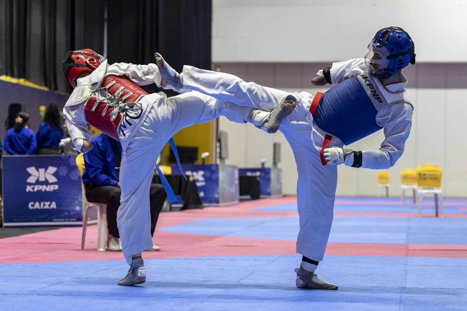 Dois atletas de parataekwondo, com protetores vermelho e azul, trocam chutes no Campeonato Brasileiro, no CT Paralímpico, em São Paulo.
